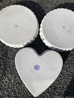 Bottom view of two round plates and one heart-shaped plate showing the KIA mark.