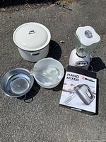 Full view of all kitchen items including hand mixer box, blender, ceramic pot, glass bowl, and metal saucepan.