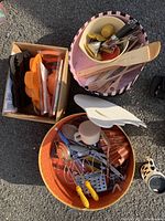 Wide view of multiple containers with assorted kitchen tools and utensils including wooden spoons, a metal whisk, measuring cups and peelers.