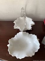 Clear glass basket with ruffled edges and a clear handle shaped like bamboo, shown from above on a wooden surface.