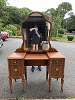 Front view of the wooden vanity with large mirror, showing four drawers and decorative legs