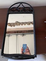 Wrought iron mirror with rectangular shape, arched top, decorative scrolls, and twisted rope iron detailing around edges.