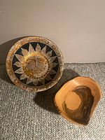 Photo showing both the sun face bowl and the wooden bowl together for size comparison and detail view.