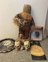 Photo showing scarecrow, skull decorations, Halloween flags, and a boxed battery-operated spider