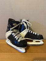 Front and side view of the pair of worn CCM youth hockey skates size 11.5 with visible wear and tear on toe caps and sides.