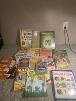 Photo showing a collection of 17 kids educational books arranged on carpeted floor against beige wall.