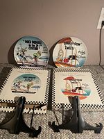 Two collectible Looney Tunes plates displayed upright with their original box packaging behind each plate, showing details of the plate artwork and the boxes