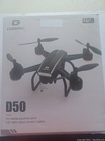 Front image of DEERC D50 drone box showing product image and key features including 120° wide-angle HD WiFi camera and recommended age 14+.