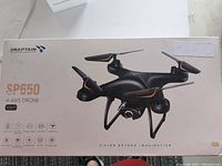 Original packaging box of the SNAPTAIN SP650 4-axis drone showing the drone image, branding, and feature icons.