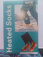 Front of retail packaging for heated socks, showing product name, an image of winter outdoor use, and flaming socks graphic.