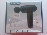 Front of box showing mini massage gun with one ball-shaped attachment head and product features.