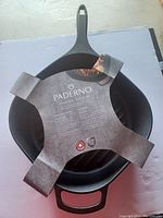 Top-down view of the Paderno cast iron grill pan with cardboard sleeve showing brand and product details.