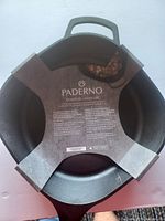 Top view of black cast iron skillet with original Paderno packaging inside.