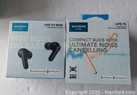 Photo of boxed Soundcore Life P2 Mini and Life P3 earbuds showing front packaging highlighting battery life, noise cancelling feature, and AI-enhanced calls.