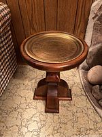 Front view of the wooden cocktail table with brass tray on top, positioned near a wall and floor with casework.