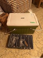 Photo showing closed Coleman cooler with cast metal hibachi grill grates placed in front.
