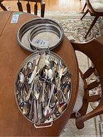 Photo showing assorted stainless and silver cutlery in Rogers pattern arranged on a metal tray.