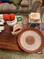 View of entire lot showing ceramic bowl, ashtrays, conch shell, glass vases, maracas, and container on wooden table.