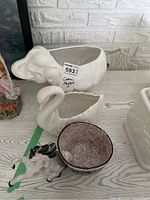 Three ceramic planters displayed on a surface: an elephant-shaped planter, a swan-shaped planter, and a smaller speckled bowl planter.