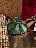 Full view of the stained glass hanging lamp shade resting on a cardboard box next to furniture.