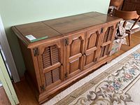 View of vintage Electrohome stereo cabinet showing front with closed wooden paneled doors and decorative wooden legs.