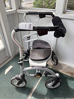 Walker Evolution portable rolling walker with padded handles, mesh backrest, and molded plastic seat shown from side angle.
