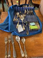 Full set of flatware laid out in blue felt-lined storage board showing dinner forks, salad forks, knives, spoons, teaspoons, and serving pieces