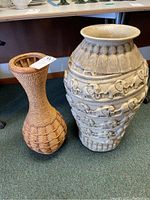 Photo of both large vases on carpet floor, showing wicker vase and ceramic vase with elephant reliefs.
