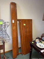 Full view of deconstructed wooden headboard and footboard standing upright against the wall
