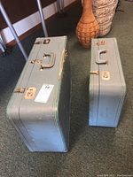 Two blue vintage hard shell luggage cases stacked with smaller inside larger for storage.