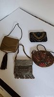 Four vintage beaded handbags and coin purse displayed on white background.
