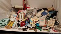 Full view of all sewing notions, tools, buttonholer templates, patches and handheld sewing machines arranged on flat surface.