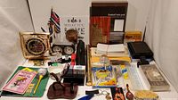 Full view of lot including Seiko clock, carved pencils, wall art, pens, calculator, notepads, envelopes, and other office supplies
