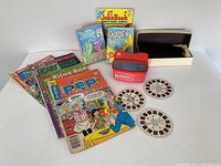 Lot items arranged for overview showing comics, books, View Master, reels, and Archie Joke Book.