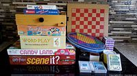 Stack of boxed board and card games including Harry Potter DVD Game, Candy Land, Scene It?, Trivial Pursuit Kids, Word Play, Hi-Q and others.