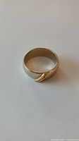Front view of gold wedding band laid flat