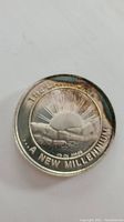 Close-up photo of 2000 silver millennium coin with visible tarnish showing the rising sun design and inscriptions.