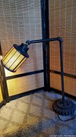 Full view of the steampunk adjustable lamp with amber shade, showing its industrial pipe-like body and gear base.