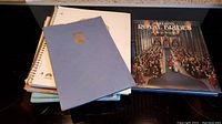 Photo showing assorted notebooks stacked with the book 'Britain's Royal Brides' on the side, featuring a blue embossed notebook visible on top.