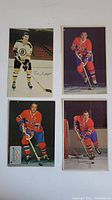 Four vintage hockey player postcards arranged in a rectangular layout. Players wear Boston Bruins and Montreal Canadiens uniforms. Each card includes player signatures.