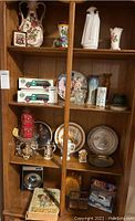 Photo of wooden display cabinet filled with various vases, plates, candles, figurines, and two Ertl die-cast truck car banks.