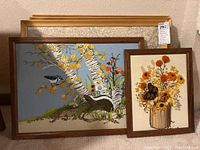 Framed textile and vintage map artworks arranged leaning against a wall, showing all three pieces in one view.
