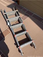 Top view of folded aluminum ladder with multi-position hinges and rubber feet ends.