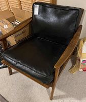 Front three-quarter view of armchair showing wood frame and black vinyl cushions