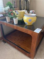 Front-side view showing table’s overall design, wood finish, black glass inset top and lower shelf