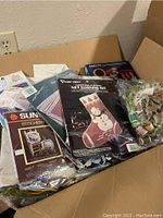 Box containing various brand new needlecraft kits in original packaging, including Christmas themed and other designs
