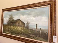 Wide angled photo showing one oil painting with rustic barn and fence in a gold-tone frame