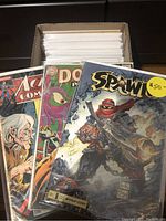 Front view of several bagged comics (Action, Doom Patrol, Spawn) standing in box