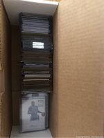 Box containing over 90 sports cards stored in sleeves and top-loaders