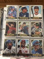 Photo of MLB baseball cards in plastic sleeves showing cards for Alonso, Machado, Lindor, Gallen, Berrios, Chapman, Lewis, Aquino, and Hoerner.